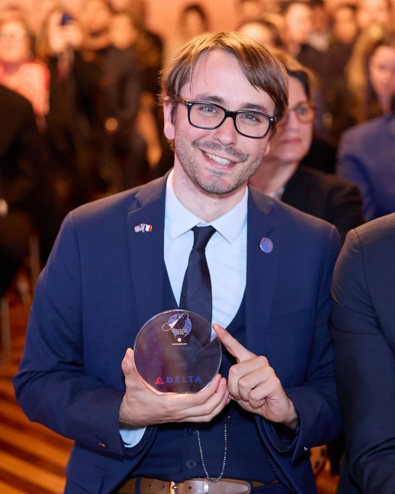 Julien P. Icher smiling and holding an award at an event